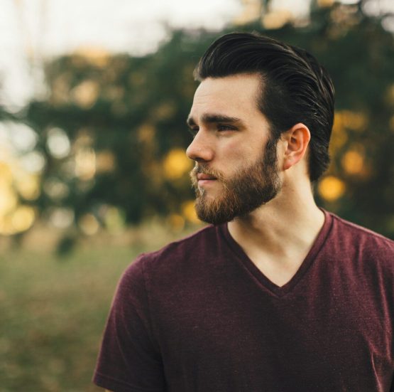 man wearing maroon V-neck t-shirt in forest