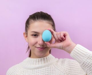 woman in white sweater holding blue egg