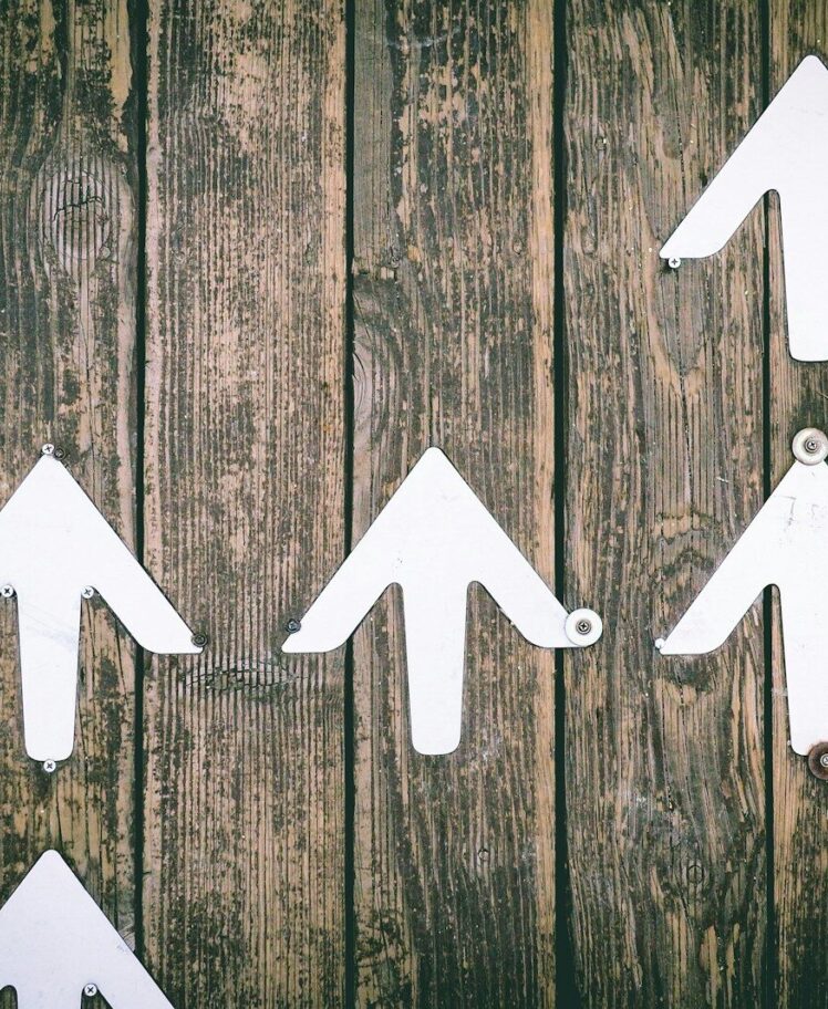 Several white arrows pointing upwards on a wooden wall