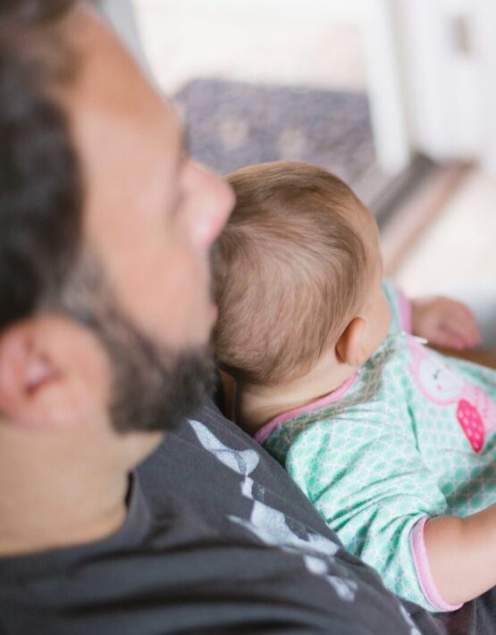 person carrying baby while reading book