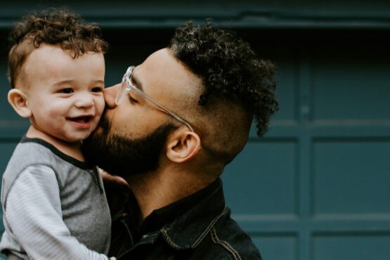 Photo by Kelly Sikkema man carrying baby boy and kissing on cheek