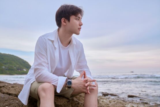 Photo by Hency Jing A man sitting on a rock near the ocean