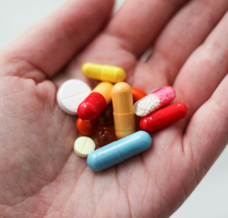 orange and white medication pill on persons hand